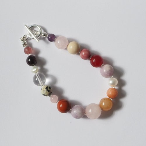 Each One Amelie Bracelet: a mix of natural gemstones including Jasper, Fossil, Quartz, Jade, Garnet, Rhodochrosite, Lepidolite, Amethyst, Unakite and Freshwater Pearl with toggle closure.